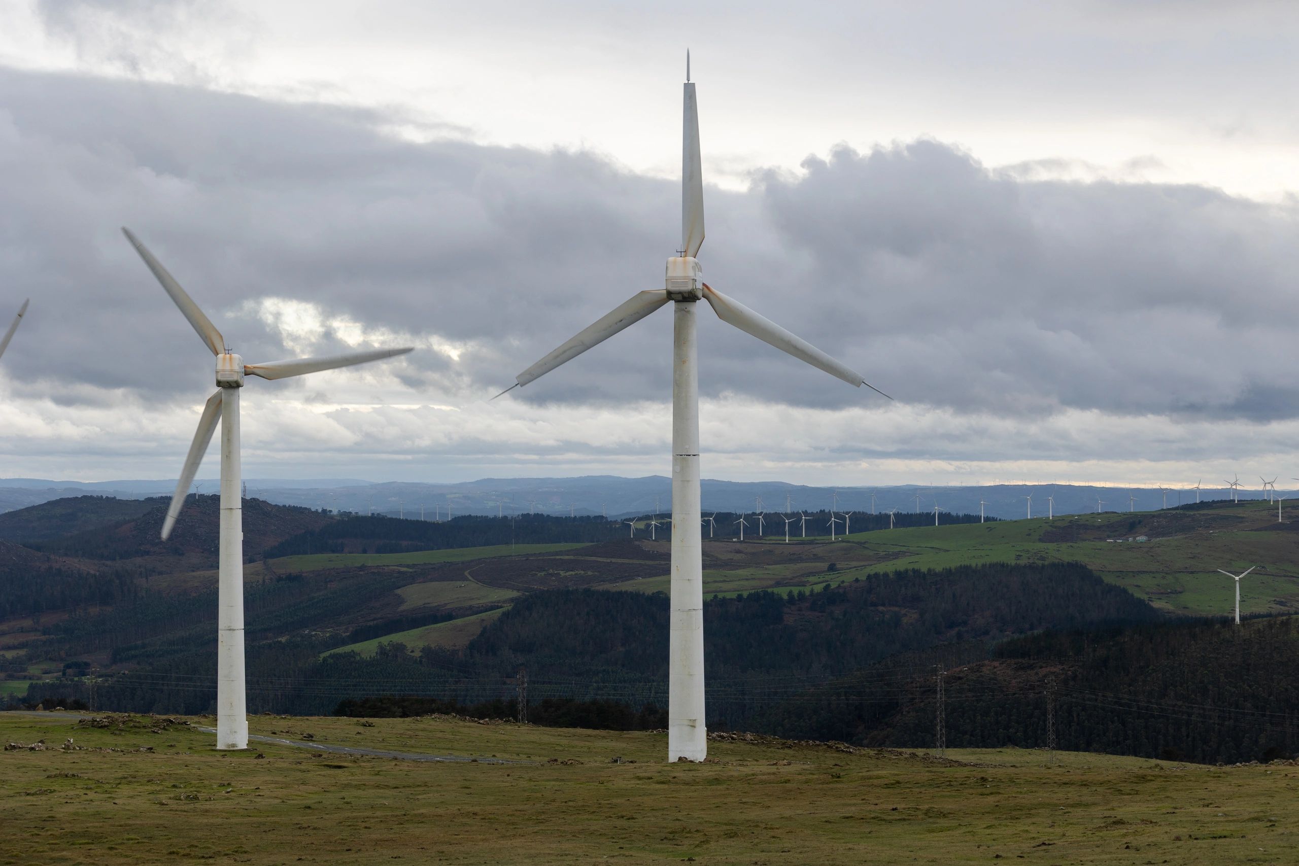 Wind turbines on rolling hills under a cloudy sky